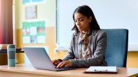 Teacher working at her desk on a laptop using AI to support PBL